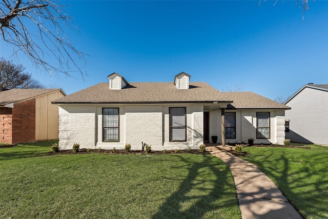 view of front of house featuring a shingled roof, brick siding, and a front lawn