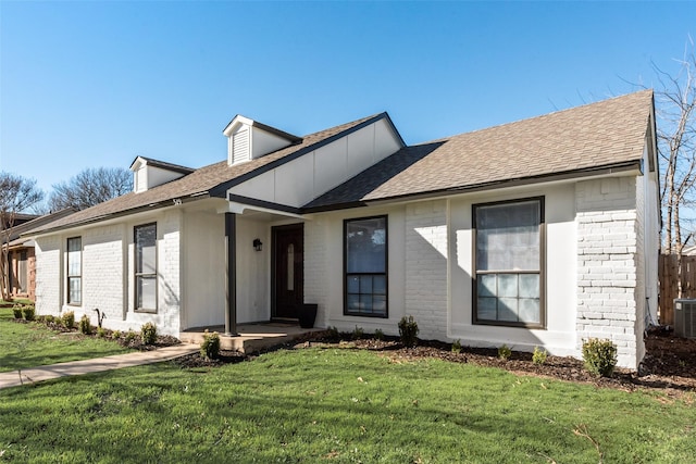 view of front of property with a shingled roof, brick siding, and a front lawn