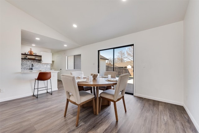 dining space with lofted ceiling, recessed lighting, wood finished floors, and baseboards