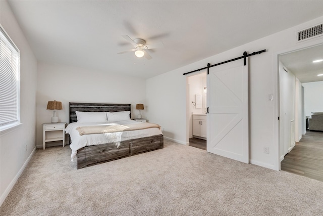 carpeted bedroom with a barn door, multiple windows, visible vents, and baseboards