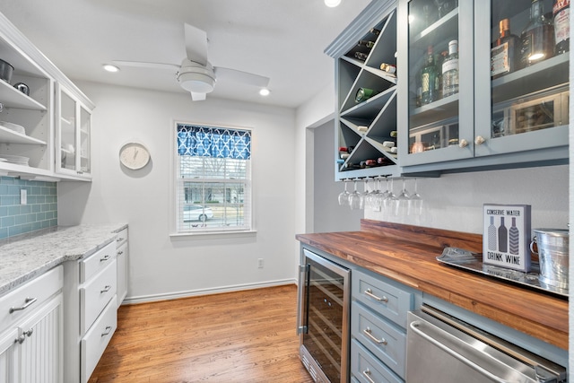 bar with a dry bar, tasteful backsplash, ceiling fan, wine cooler, and light wood-style floors