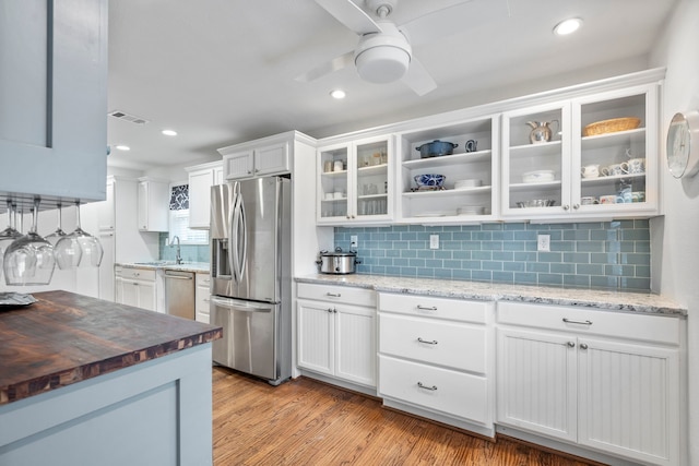 kitchen with white cabinets, visible vents, glass insert cabinets, and stainless steel appliances