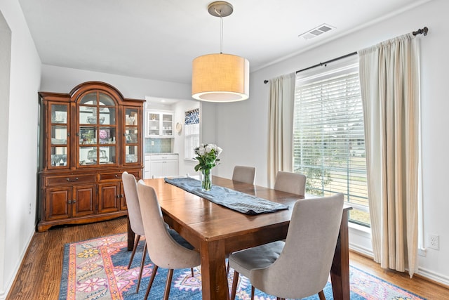 dining area featuring wood finished floors, visible vents, and baseboards