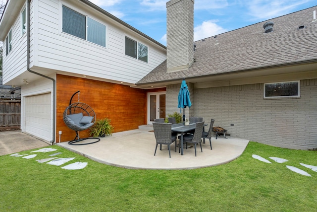 back of property with brick siding, a yard, a chimney, roof with shingles, and a patio area