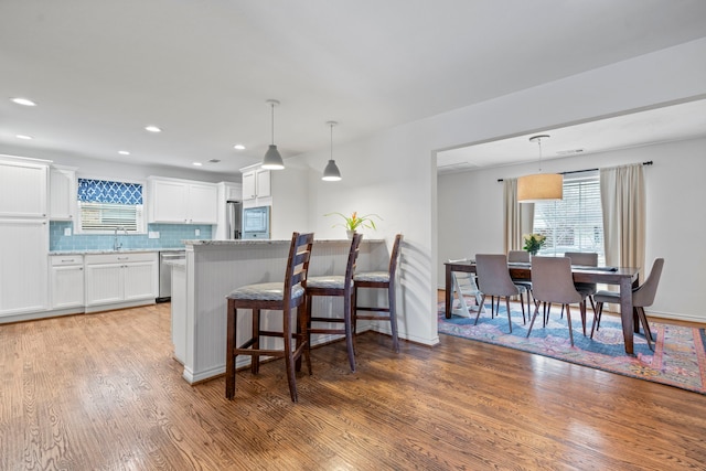 kitchen featuring tasteful backsplash, light wood-style flooring, appliances with stainless steel finishes, white cabinets, and a sink