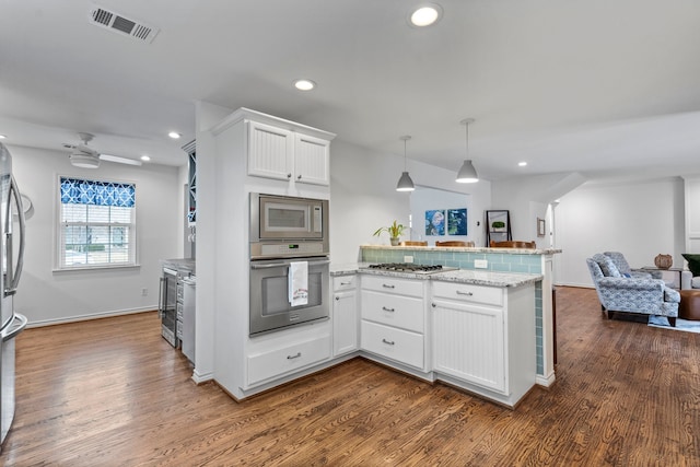 kitchen featuring visible vents, appliances with stainless steel finishes, open floor plan, white cabinetry, and a peninsula