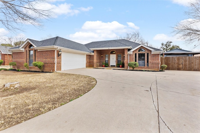 view of front facade featuring brick siding, a shingled roof, concrete driveway, fence, and a garage