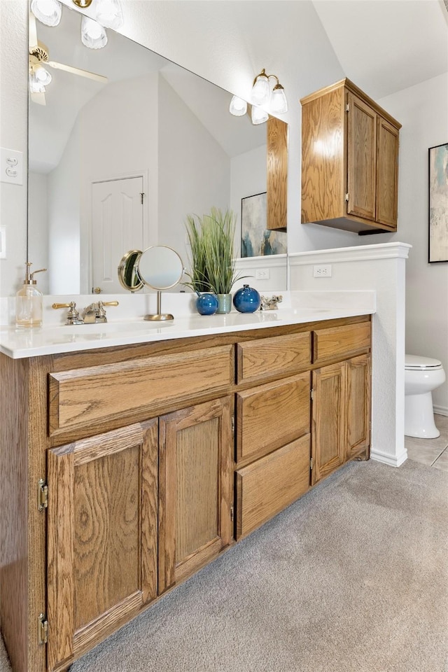 bathroom with lofted ceiling, double vanity, a sink, and toilet