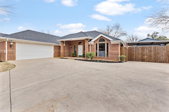 view of front of home with concrete driveway, brick siding, roof with shingles, and fence