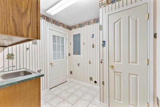 entryway with light tile patterned floors, a sink, electric panel, baseboards, and wallpapered walls