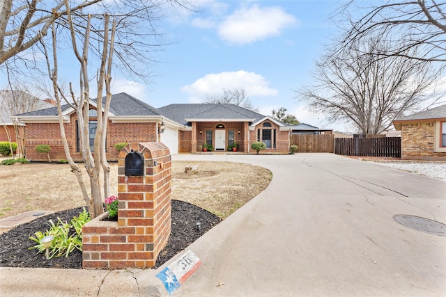 view of front of house with brick siding, roof with shingles, concrete driveway, an attached garage, and fence