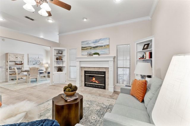 living room featuring visible vents, a tiled fireplace, ceiling fan, ornamental molding, and built in shelves