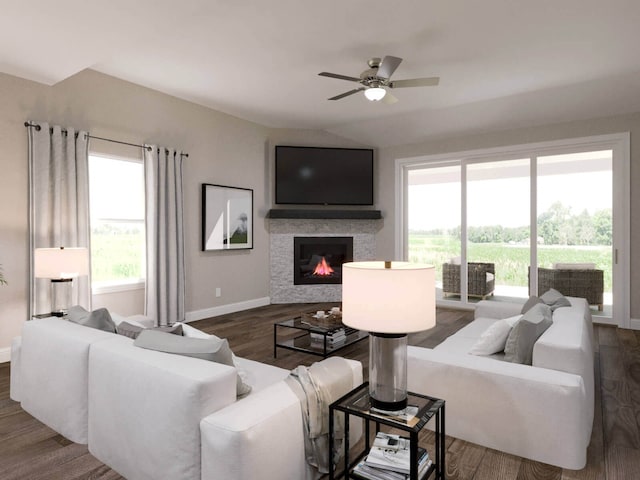 living area featuring a ceiling fan, a glass covered fireplace, vaulted ceiling, wood finished floors, and baseboards