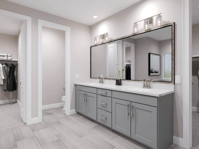 bathroom featuring a walk in closet, a sink, toilet, and double vanity