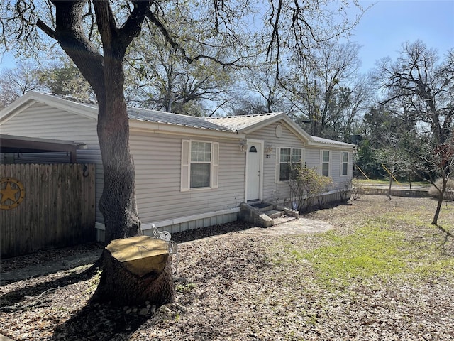 manufactured / mobile home with entry steps, fence, and metal roof