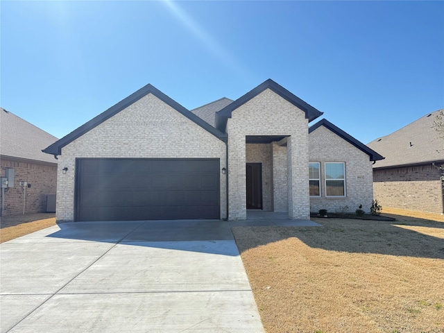 ranch-style house with a garage, concrete driveway, brick siding, and a front yard