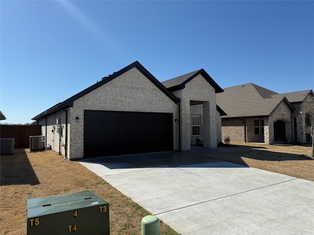 view of front of home with an attached garage, driveway, central AC, and brick siding