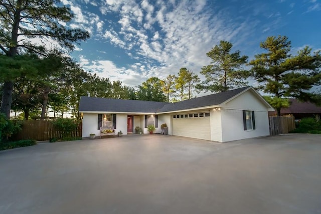 ranch-style house featuring driveway, a garage, and fence