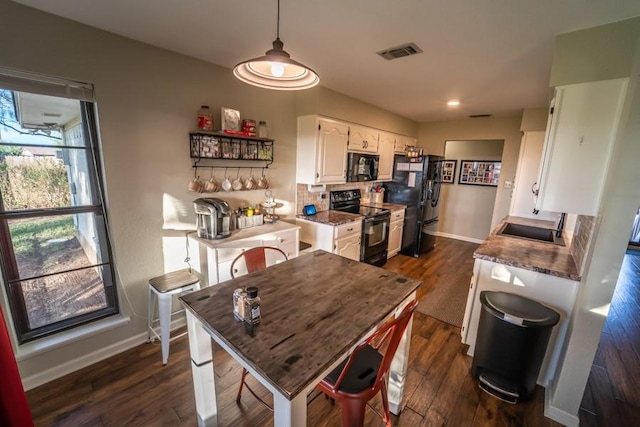 kitchen featuring visible vents, dark wood-style floors, black appliances, white cabinetry, and a sink