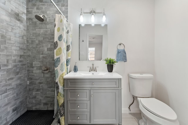 bathroom featuring toilet, vanity, tiled shower, baseboards, and tile patterned floors