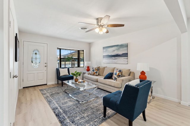 living area featuring light wood finished floors, baseboards, visible vents, and a ceiling fan