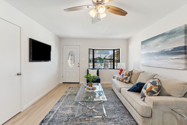 living room featuring light wood-style flooring, baseboards, and a ceiling fan