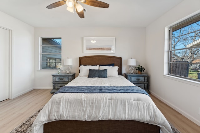 bedroom with ceiling fan, multiple windows, wood finished floors, and baseboards