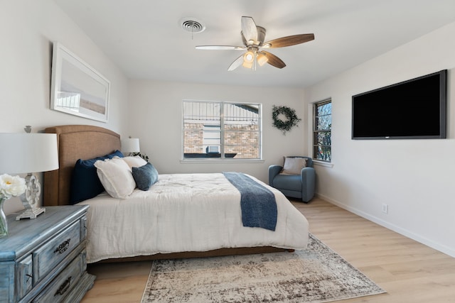 bedroom featuring ceiling fan, light wood finished floors, visible vents, and baseboards