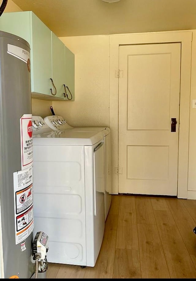 508 N Tackitt St, Seymour, TX 76380 - laundry area with cabinet space, gas water heater, washing machine and clothes dryer, and light wood-style floors