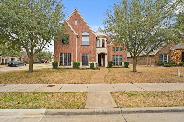 view of front facade featuring brick siding and a front yard