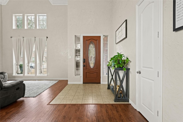 entrance foyer with baseboards, wood finished floors, and a textured wall