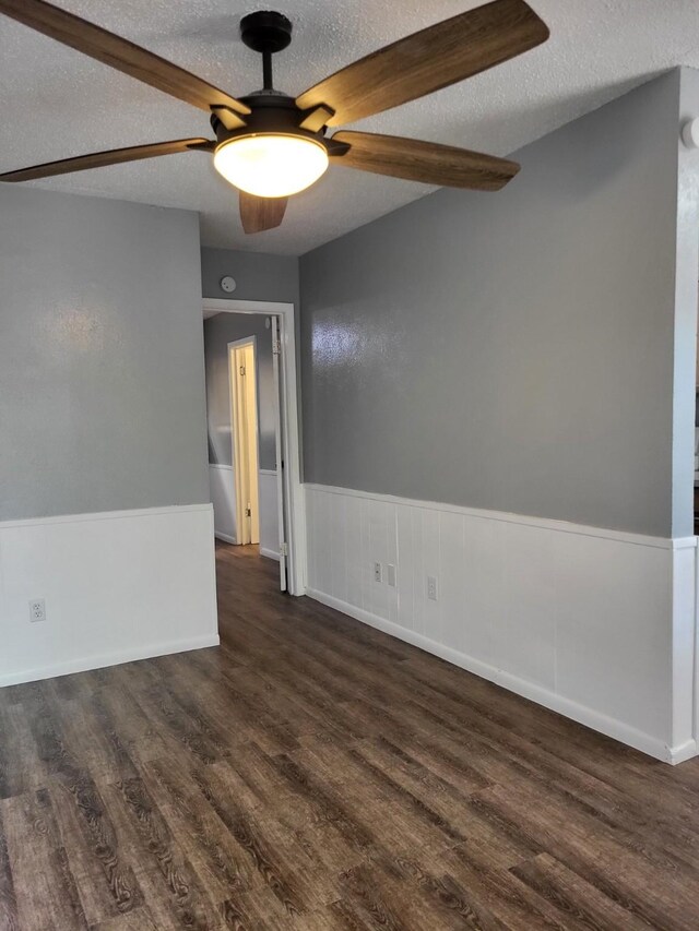 empty room featuring a wainscoted wall, ceiling fan, a textured ceiling, and wood finished floors
