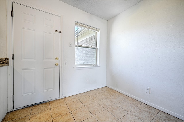 foyer with light tile patterned floors, a textured ceiling, and baseboards