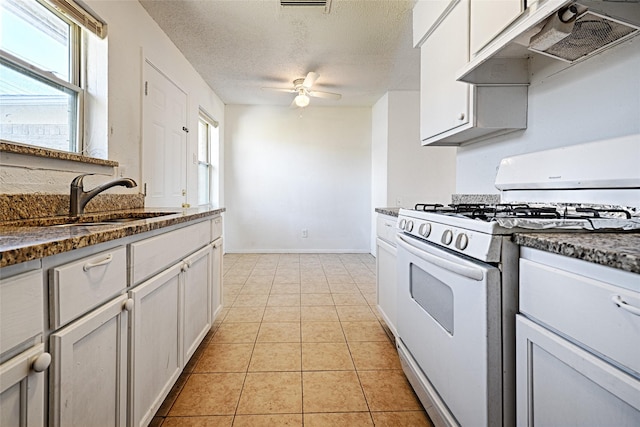 kitchen featuring light tile patterned floors, white range with gas cooktop, a textured ceiling, under cabinet range hood, and a sink