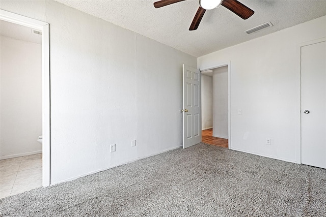 unfurnished bedroom featuring a textured ceiling, ceiling fan, carpet, and visible vents