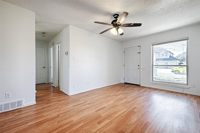 unfurnished room with baseboards, visible vents, a ceiling fan, light wood-style flooring, and a textured ceiling