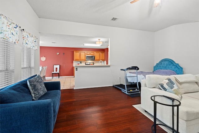 living room featuring baseboards, ceiling fan, visible vents, and wood finished floors