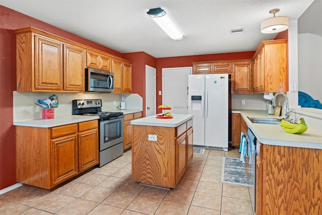 kitchen with light tile patterned floors, stainless steel appliances, light countertops, a sink, and a kitchen island