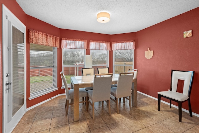 tiled dining room featuring baseboards, a textured ceiling, and a textured wall