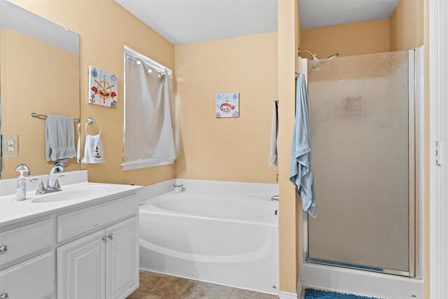 bathroom with a stall shower, vanity, a textured ceiling, tile patterned flooring, and a bath