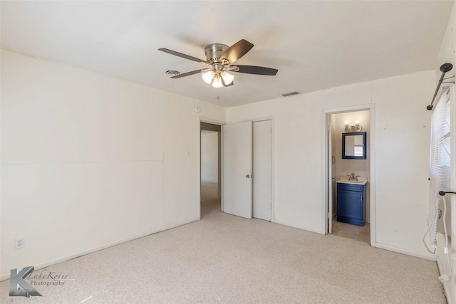 unfurnished bedroom featuring visible vents, a ceiling fan, light colored carpet, ensuite bathroom, and a sink