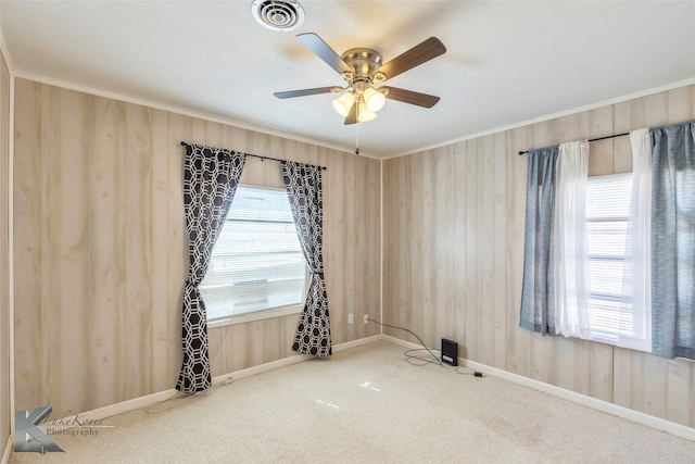 empty room with ornamental molding, a wealth of natural light, carpet, and visible vents