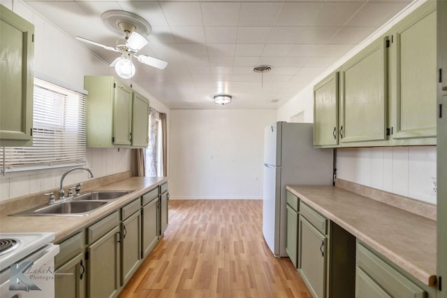 kitchen featuring visible vents, a sink, light wood finished floors, and green cabinets