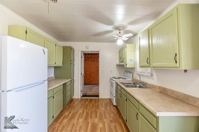 kitchen with white appliances, light countertops, light wood-type flooring, green cabinets, and a sink