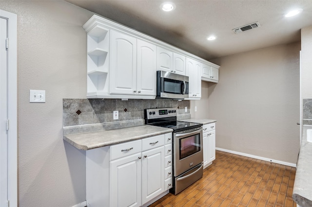 kitchen with stainless steel appliances, tasteful backsplash, open shelves, and light countertops