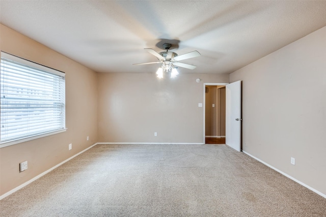 empty room with carpet floors, ceiling fan, and baseboards