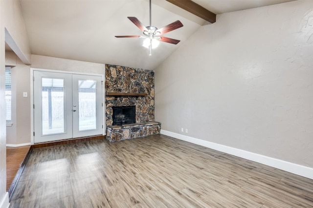 unfurnished living room featuring vaulted ceiling with beams, a fireplace, wood finished floors, and french doors