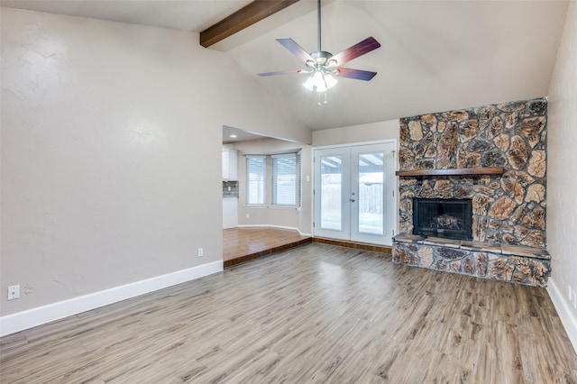 unfurnished living room with baseboards, lofted ceiling with beams, wood finished floors, french doors, and a fireplace