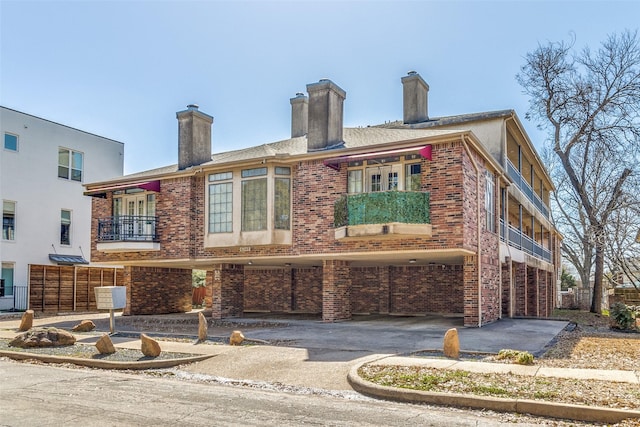 exterior space with aphalt driveway, brick siding, and a chimney