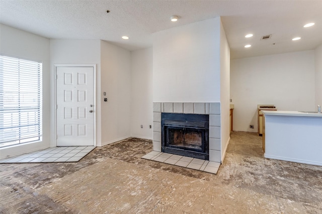 unfurnished living room with a fireplace, recessed lighting, visible vents, a sink, and a textured ceiling